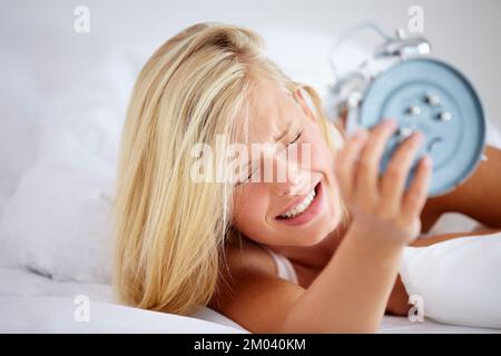 Nein, ich brauche eine Schlummertaste. Verärgerte Frau, die ihren Wecker hält, mit einem Ausdruck der Frustration. Stockfoto