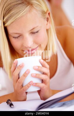 Es geht nichts über den Geruch von frisch gebrühtem Kaffee. Junge Frau, die eine Tasse Kaffee riecht, während sie sich hinlegte. Stockfoto