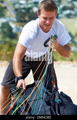 Ich bereite mich auf einen reibungslosen Start vor. Ein Mann, der an einem sonnigen Tag Paragliding fährt. Stockfoto