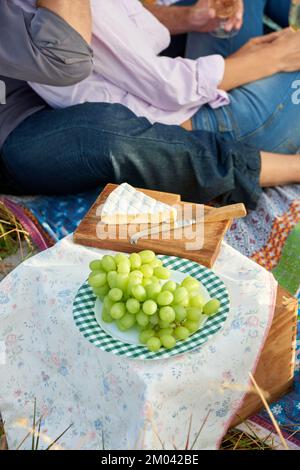 Nichts ist romantischer als ein Picknick. Ein liebevolles Paar, das zusammen ein gemütliches Picknick auf einem malerischen Feld genießt. Stockfoto