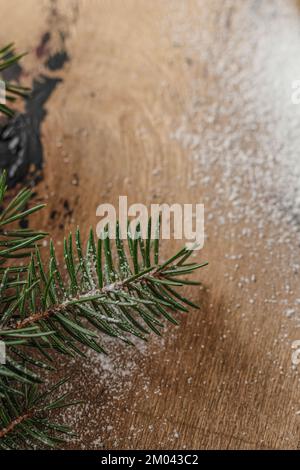 Tannenzweig auf schneebedeckten Holzhintergrund. Textbereich. Weihnachtskarte, Tapete Stockfoto