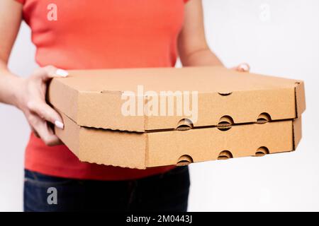 Ein Mädchen, das Pizza in Pappkartons auf weißem Hintergrund liefert Stockfoto