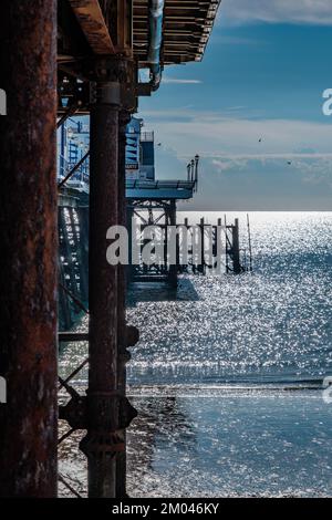 Ein Blick auf den Eastbourne Pier im frühen Morgensonnenlicht, das auf dem Meer glitzert. Stockfoto