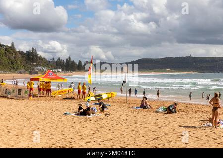 Freiwillige Surferrettung am Palm Beach in Sydney an einem Sommertag 2022, Barrenjoey Landzunge und Leuchtturm in der Ferne, NSW, Australien Stockfoto