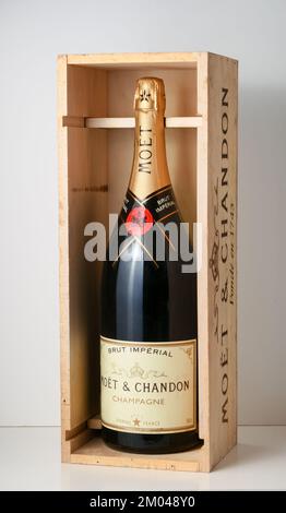 Glasflasche mit brut, funkelnden Moet und Chandon in einer Holzkiste auf grauem Hintergrund Stockfoto