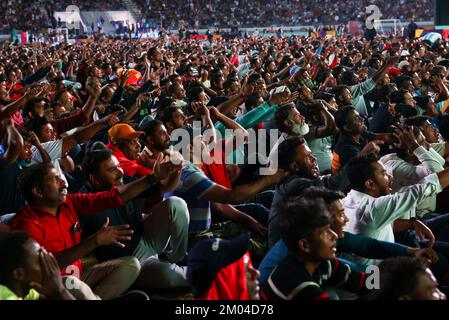 Doha, Katar. 03.. Dezember 2022. Arbeiter, hauptsächlich aus Indien, Bangladesch, Nepal und anderen ärmeren asiatischen Ländern, sehen das Spiel Argentinien-Australien auf einer großen Leinwand im Asian Town Cricket Stadium. Im Cricket-Stadion, das offiziell als „Fan Zone Industrial Area“ bezeichnet wird, sehen sich jeden Abend Tausende von ausländischen Arbeitern die Fußballspiele der Weltmeisterschaft an. Kredit: Christian Charisius/dpa/Alamy Live News Stockfoto