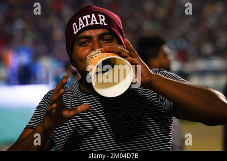 Doha, Katar. 03.. Dezember 2022. Arbeiter, hauptsächlich aus Indien, Bangladesch, Nepal und anderen ärmeren asiatischen Ländern, sehen das Spiel Argentinien-Australien auf einer großen Leinwand im Asian Town Cricket Stadium. Im Cricket-Stadion, das offiziell als „Fan Zone Industrial Area“ bezeichnet wird, sehen sich jeden Abend Tausende von ausländischen Arbeitern die Fußballspiele der Weltmeisterschaft an. Kredit: Christian Charisius/dpa/Alamy Live News Stockfoto