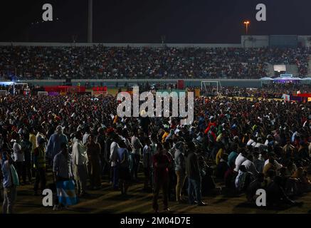 Doha, Katar. 03.. Dezember 2022. Arbeiter, hauptsächlich aus Indien, Bangladesch, Nepal und anderen ärmeren asiatischen Ländern, sehen das Spiel Argentinien-Australien auf einer großen Leinwand im Asian Town Cricket Stadium. Im Cricket-Stadion, das offiziell als „Fan Zone Industrial Area“ bezeichnet wird, sehen sich jeden Abend Tausende von ausländischen Arbeitern die Fußballspiele der Weltmeisterschaft an. Kredit: Christian Charisius/dpa/Alamy Live News Stockfoto