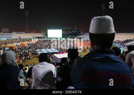 Doha, Katar. 03.. Dezember 2022. Arbeiter, hauptsächlich aus Indien, Bangladesch, Nepal und anderen ärmeren asiatischen Ländern, sehen das Spiel Argentinien-Australien auf einer großen Leinwand im Asian Town Cricket Stadium. Im Cricket-Stadion, das offiziell als „Fan Zone Industrial Area“ bezeichnet wird, sehen sich jeden Abend Tausende von ausländischen Arbeitern die Fußballspiele der Weltmeisterschaft an. Kredit: Christian Charisius/dpa/Alamy Live News Stockfoto