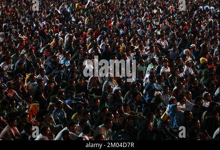Doha, Katar. 03.. Dezember 2022. Arbeiter, hauptsächlich aus Indien, Bangladesch, Nepal und anderen ärmeren asiatischen Ländern, sehen das Spiel Argentinien-Australien auf einer großen Leinwand im Asian Town Cricket Stadium. Im Cricket-Stadion, das offiziell als „Fan Zone Industrial Area“ bezeichnet wird, sehen sich jeden Abend Tausende von ausländischen Arbeitern die Fußballspiele der Weltmeisterschaft an. Kredit: Christian Charisius/dpa/Alamy Live News Stockfoto