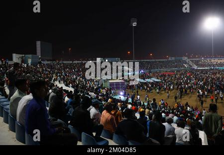 Doha, Katar. 03.. Dezember 2022. Arbeiter, hauptsächlich aus Indien, Bangladesch, Nepal und anderen ärmeren asiatischen Ländern, sehen das Spiel Argentinien-Australien auf einer großen Leinwand im Asian Town Cricket Stadium. Im Cricket-Stadion, das offiziell als „Fan Zone Industrial Area“ bezeichnet wird, sehen sich jeden Abend Tausende von ausländischen Arbeitern die Fußballspiele der Weltmeisterschaft an. Kredit: Christian Charisius/dpa/Alamy Live News Stockfoto
