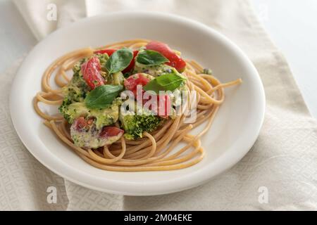 Vollkornspaghetti mit Brokkoli und Tomatensoße und Basilikumgarnierung, gesunde vegetarische hausgemachte Küche, ausgewählter Fokus, kleine Tiefe des Tortes Stockfoto