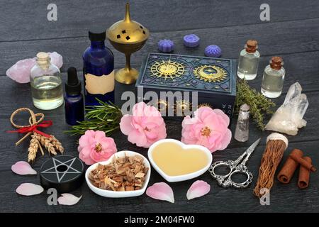 Heidnische Liebestrank Aphrodisiakrezepte mit Kräutern, Rosenblüten, Maisdolly, Öl, Quellwasser und Quarzkristallen. Stockfoto