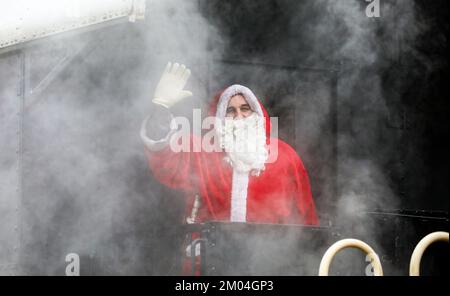 04. Dezember 2022, Baden-Württemberg, Münsingen: Ein Mann verkleidet als St. Nicholas steht auf der Plattform eines historischen Wagens in der Rauchwolke des St. Der Dampfzug von Nicholas wurde von einer Dampflokomotive des Typs T3 gezogen, die 1905 gebaut wurde. Foto: Thomas Warnack/dpa Stockfoto