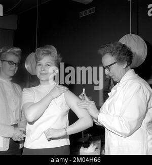 Impfstoff in den 1960er Jahren. Eine Krankenschwester injiziert einer jungen Frau einen Impfstoff in den Arm. Schweden 1965 Conard Ref 5011 Stockfoto