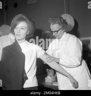 Impfstoff in den 1960er Jahren. Eine Krankenschwester injiziert einer jungen Frau einen Impfstoff in den Arm. Schweden 1965 Conard Ref 5011 Stockfoto