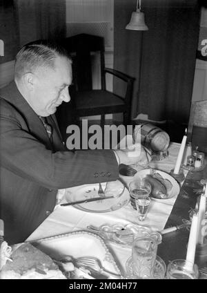 zu weihnachten in den 1940er. Ein Mann isst zu weihnachten zu Abend und genießt die typischen traditionellen Speisen und Getränke vom Tisch. Schweden dezember 1940 Kristoffersson 42-9 Stockfoto