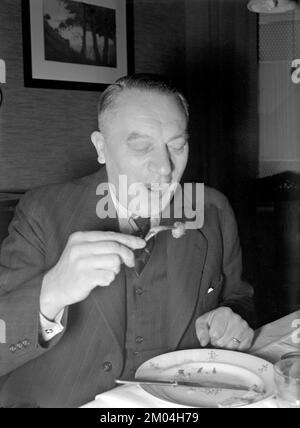 zu weihnachten in den 1940er. Ein Mann isst zu weihnachten und hat ein Fleischklößchen auf der Gabel. Schweden dezember 1940 Kristoffersson 42-10 Stockfoto