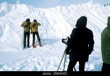 Mode in den 1980er Jahren. Zwei junge männliche Models stehen im Schnee für ein Fotoshooting. Sie tragen warme Winterjacken und -Hosen und einer davon die jahrzehntelangen typischen Winterstiefel. Schweden märz 1980 Stockfoto