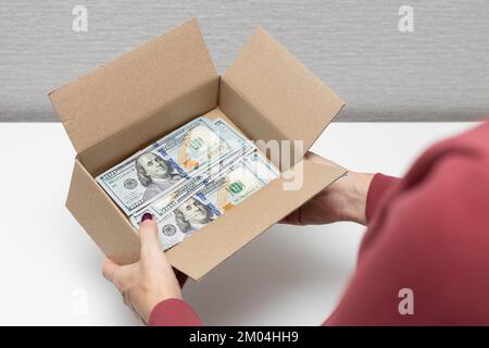 Ein Mann hält eine Kiste, in der Dollars sind. Geldkiste. Stockfoto