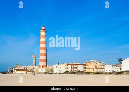 Sonnige Aussicht auf die kleine Strandstadt Praia da Barra, alter Leuchtturm, leerer Strand, helle kleine Häuser Aveiro, Portugal Stockfoto