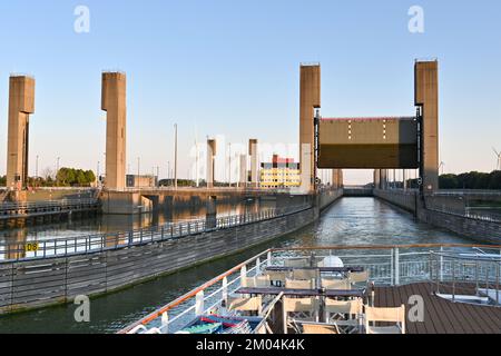 Rilland, Niederlande - August 2022: Flussschiff verlässt eine große Kanalschleuse mit angehobenem Schleusentor Stockfoto