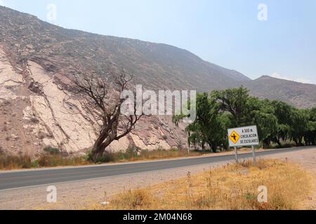 Unbefestigte Straße, die zwischen Bergen verloren ging. Straßen von Purmamarca, Jujuy, Argentinien. Berge von unglaublichen Farben. Landschaften Argentiniens Stockfoto