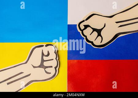 Zwei Pappfäuste auf russischen und ukrainischen Flaggen. Russland gegen die Ukraine handelte mit Streitigkeiten und Anschlägen im Dritten Weltkrieg Stockfoto