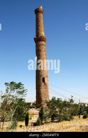 Herat in Afghanistan. Eines der Musalla-Minarette von Herat, Teil des Musalla-Komplexes. Dieses Minarett neigt sich in einem unsicheren Winkel, der von Kabeln gehalten wird. Stockfoto