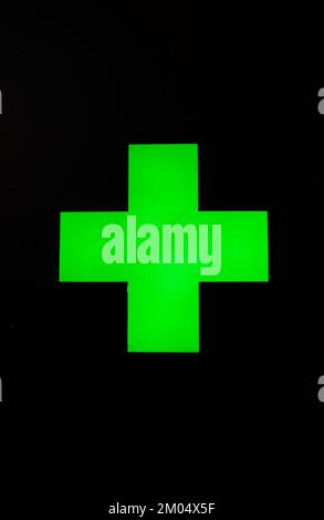 Grünes Kreuz auf schwarzem Hintergrund - das grüne Kreuz ist ein Symbol für Apotheken Stockfoto