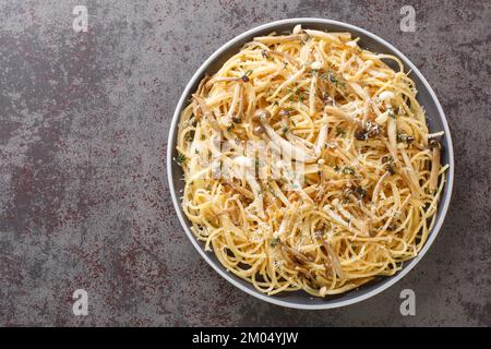 Spaghetti-Pasta mit gebratenen Shimeji-Buchenpilzen mit Parmesan und Thymian in Nahaufnahme auf einem Teller auf dem Tisch. Horizontale Draufsicht von oben Stockfoto