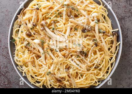 Cremige Spaghetti mit Buchenpilzen mit Parmesan und Thymian in der Nahaufnahme auf einem Teller auf dem Tisch. Horizontale Draufsicht von oben Stockfoto