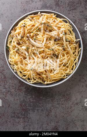 Spaghetti mit weißen und braunen Buchenpilzen mit cremiger Sauce und Thymian in Nahaufnahme auf einem Teller auf dem Tisch. Vertikale Draufsicht von oben Stockfoto