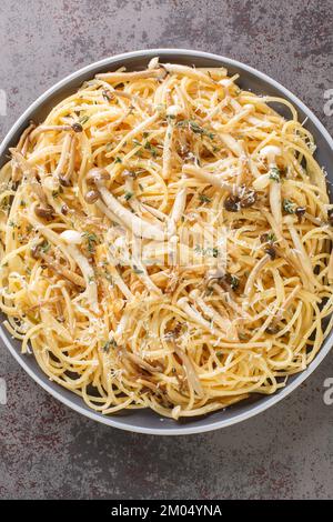 Pasta mit braunen und weißen Buchenpilzen in einer cremigen Pilzsauce und Thymian auf dem Teller. Vertikale Draufsicht von oben Stockfoto