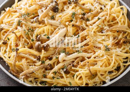 Cremige Spaghetti mit Buchenpilzen mit Parmesan und Thymian in der Nahaufnahme auf einem Teller auf dem Tisch. Horizontal Stockfoto