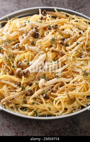 Pasta mit braunen und weißen Buchenpilzen in einer cremigen Pilzsauce und Thymian auf dem Teller. Vertikal Stockfoto