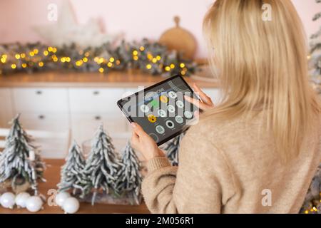 Junge Frau verwendet Anwendung in seinem Smart Home zu Weihnachten Stockfoto