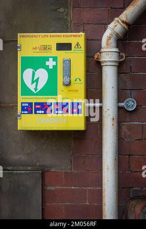 Rawtenstall, Rossendale, Lancashire, Sonntag, den 4. Dezember 2022. Defibrillator an der roten Backsteinwand der lokalen Bibliothek. Stockfoto