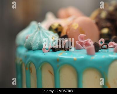 Donuts, Baiser-Beeren und Glitzer auf Milchpulver, türkisfarbener Tropfkuchen für die Geburtstagsfeier Stockfoto