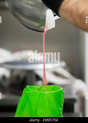Füllung mit Füllbeutel für den Konditorkoch mit essbarer rosafarbener Farbe für die Farbskala „Frosted Cake Topping“ Stockfoto