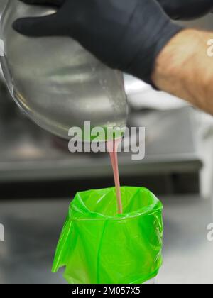 Füllung mit Füllbeutel für den Konditorkoch mit essbarer rosafarbener Farbe für die Farbskala „Frosted Cake Topping“ Stockfoto
