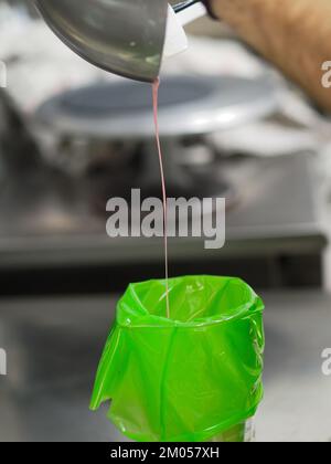 Füllung mit Füllbeutel für den Konditorkoch mit essbarer rosafarbener Farbe für die Farbskala „Frosted Cake Topping“ Stockfoto