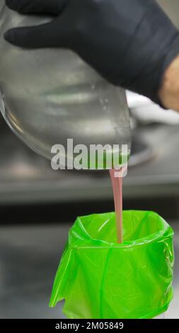 Füllung mit Füllbeutel für den Konditorkoch mit essbarer rosafarbener Farbe für die Farbskala „Frosted Cake Topping“ Stockfoto
