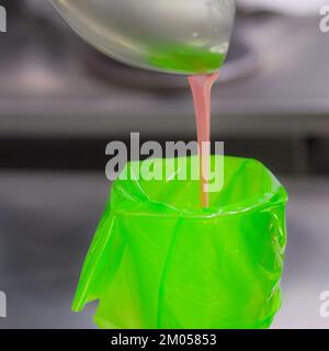 Füllung mit Füllbeutel für den Konditorkoch mit essbarer rosafarbener Farbe für die Farbskala „Frosted Cake Topping“ Stockfoto