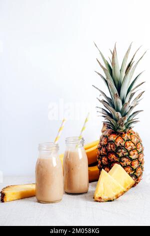 Ananas-Smoothie in Flaschen mit Zutaten. Gesunde vegane Rohkost. Weißer Hintergrund, Kopierbereich. Stockfoto