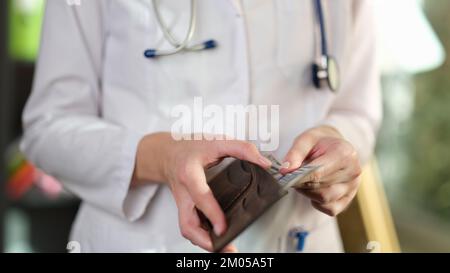 Weibliche Ärztin, die das Geld in ihrer Brieftasche zählt. Stockfoto