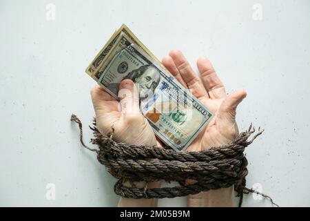 Weibliche Hände, die amerikanische Dollar halten, gefesselte Hände auf weißem Hintergrund Stockfoto