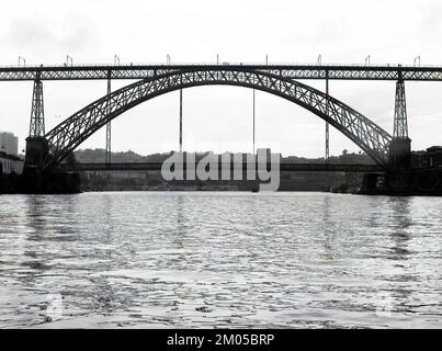 Schwarzweißfoto der Brücke Dom Lui¬bei Tag, Blick von der Mitte des Flusses Douro, Porto, Portugal. Reiseziel Stockfoto