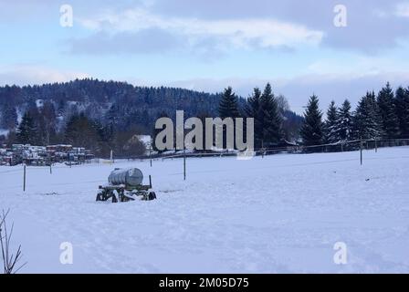 Schneebedeckte Wiese mit Wasserwagen in einem tiefschneebedeckten ländlichen Gebiet der Schwäbischen Alb im Winter, Muensingen, Baden-Württemberg, Deutschland. Stockfoto