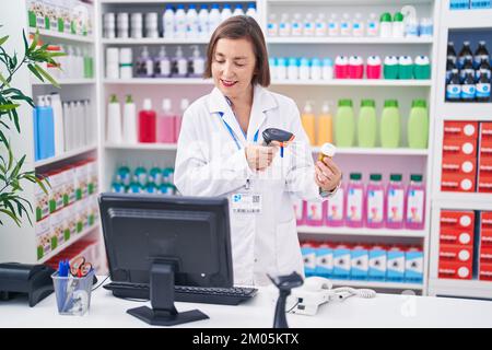 Frau mittleren Alters Apotheker Scannen Pillen Flasche in der Apotheke Stockfoto